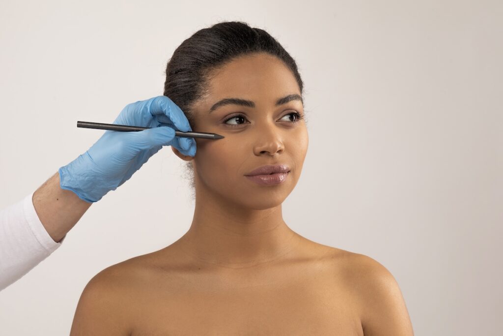 Woman looks away from camera as gloved professional marks spots for laser scar removal in OKC