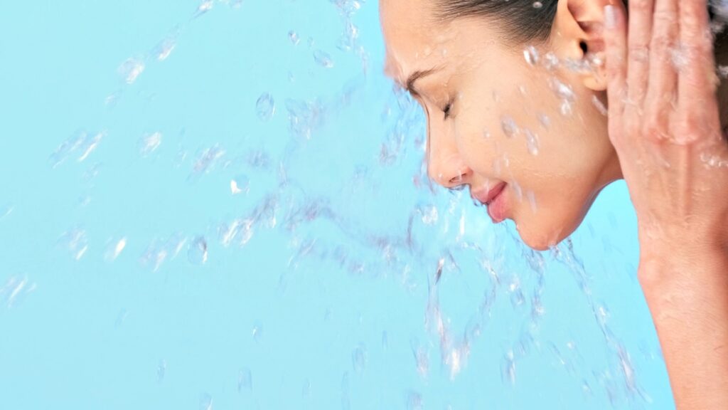 Woman washing her face and keeping it hydrated after learning about skin care in OKC