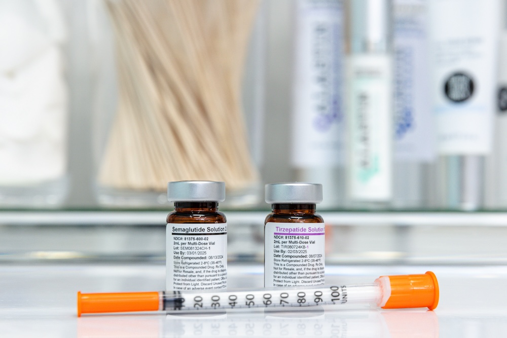 Bottles of semaglutide and tirzepatide sit on sterile countertop with a syringe placed in front of them. Both medications work as an appetite suppressant in Oklahoma City.